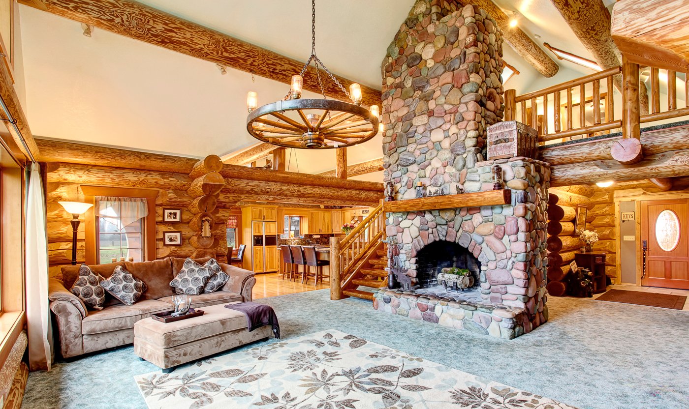 Warm log home great room with timber beams and stone fireplace